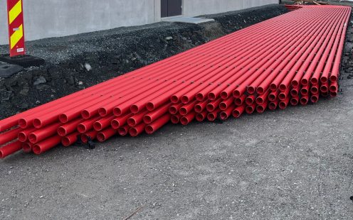 Sarkano kabeļu aizsargcauruļu kūlis ar OPI starplikām datu centra kabeļu kanālu bloka uzstādīšanas laikā